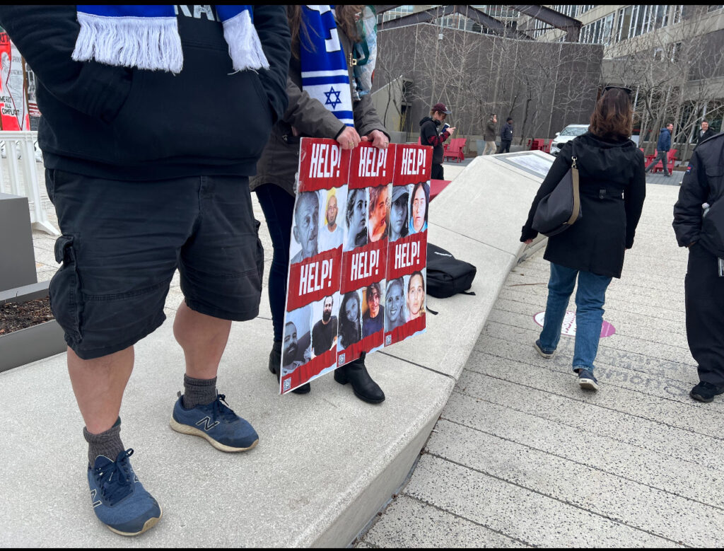 Pro-Israel counter-protestors display a poster board with the faces and names of hostages taken by Hamas following the October 7 attacks in Israel. (Tobi Omotoso, HLS '25).
