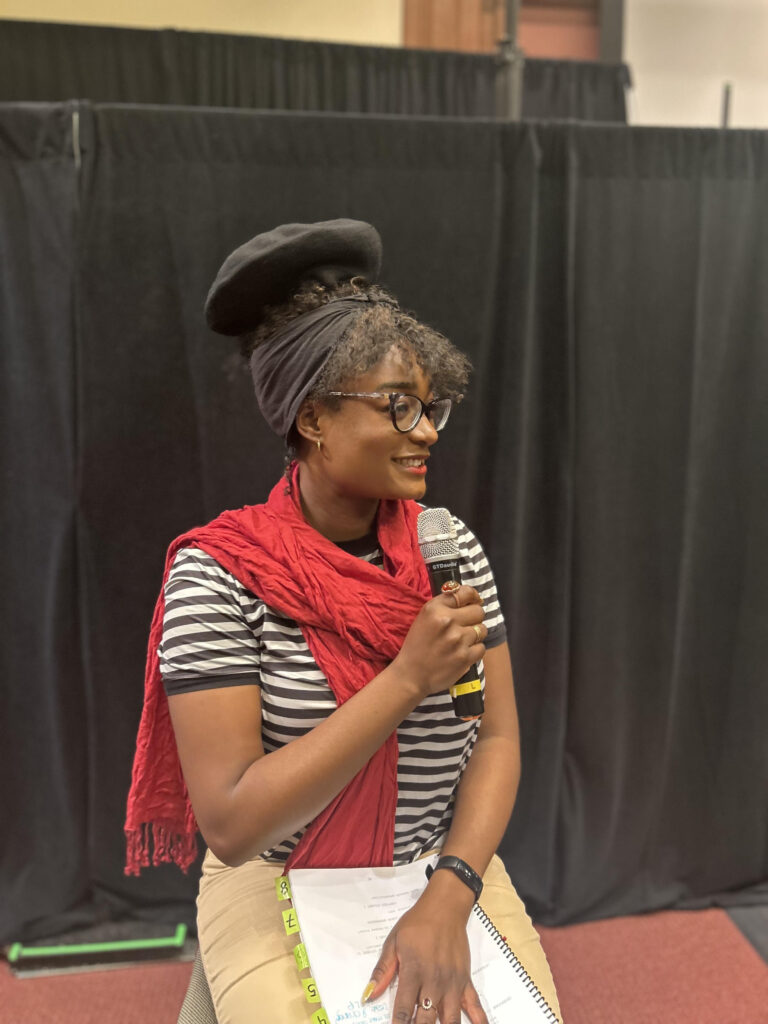 Deborah Alexis, HLS '25, as Narrator, in stereotypical French attire, including a beret, red scarf, and a black and white striped top.