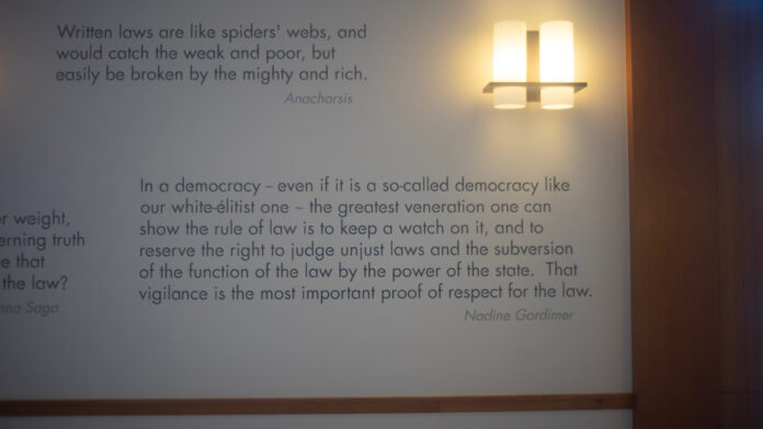Wasserstein Wall Quotes 1 Quotes on the wall inside of Wassersetein Hall related to the rule of law. The first reads: "'Written laws are like spiders' webs, and would catch the weak and poor, but easily be broken by the mighty and rich.'” -Anacharsis" The second reads: “'In a democracy - even if it is a so-called democracy like our white-élitist one - the greatest veneration one can show the rule of law is to keep a watch on it, and to reserve the right to judge unjust laws and the subversion of the function of the law by the power of the state. That vigilance is the most important proof of respect for the law.' -Nadine Gordimer"