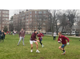 Several flag football players running in Cambridge Common park in the midst of a match. Peter Bell-Goeckner, HLS '25 (, red shirt and gray shorts), and Antoine Beaury, LLM '25 (red shirt, white shorts) prepare to engage each other in play.