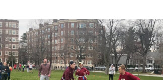 Several flag football players running in Cambridge Common park in the midst of a match. Peter Bell-Goeckner, HLS '25 (, red shirt and gray shorts), and Antoine Beaury, LLM '25 (red shirt, white shorts) prepare to engage each other in play.