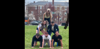 Six players stacked together in a human pyramid in Cambridge Common park.
